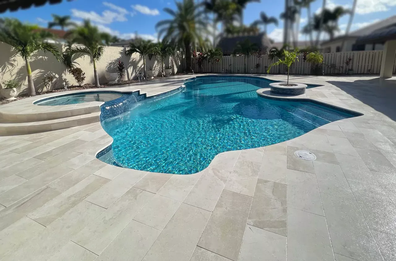 Remodeled blue swimming pool with a natural stone deck and tropical landscaping in South Florida