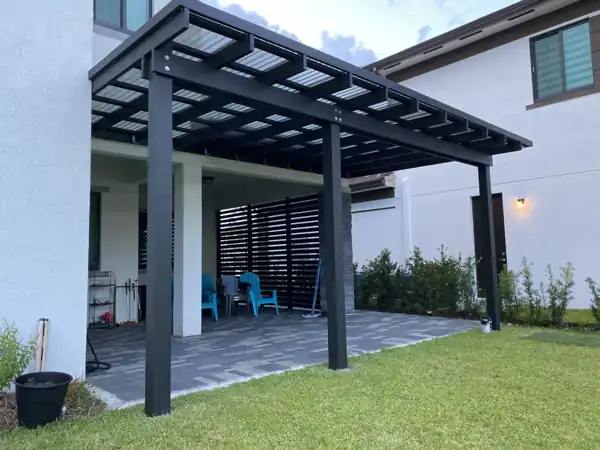 Aluminum pergola with louvered roof panels attached to the house, over a paver patio