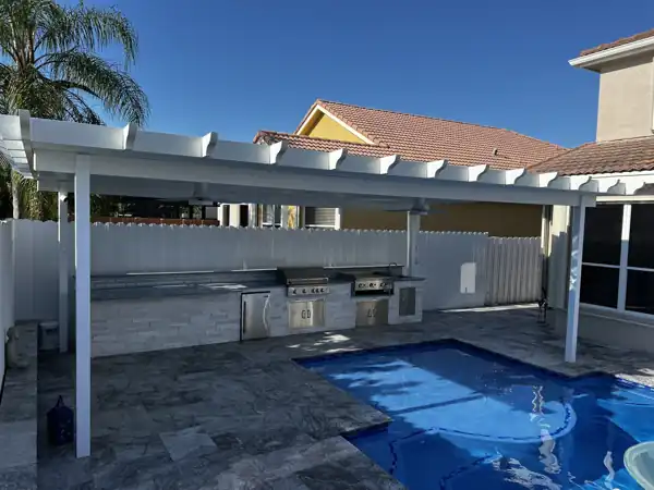 White aluminum patio cover with ceiling fans over an outdoor kitchen, poolside
