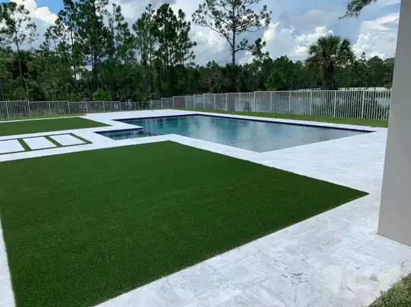 Artificial turf lawn with a paver stepping-stone inset, bordering a pool and paver deck