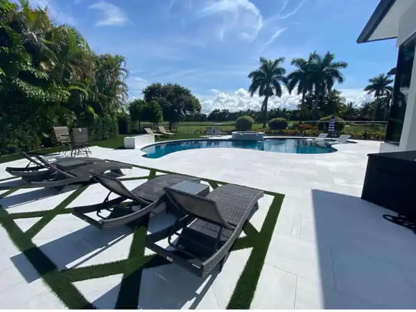 Artificial turf accent strips in a geometric pattern between pavers, poolside lounge area