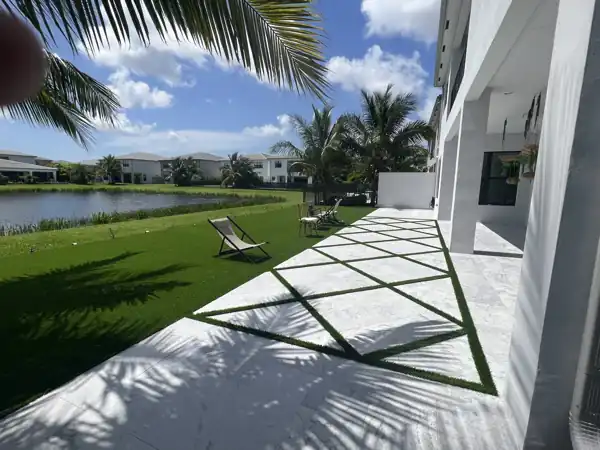 Artificial turf lawn with a diamond-pattern turf inlay between pavers on a lakefront lot